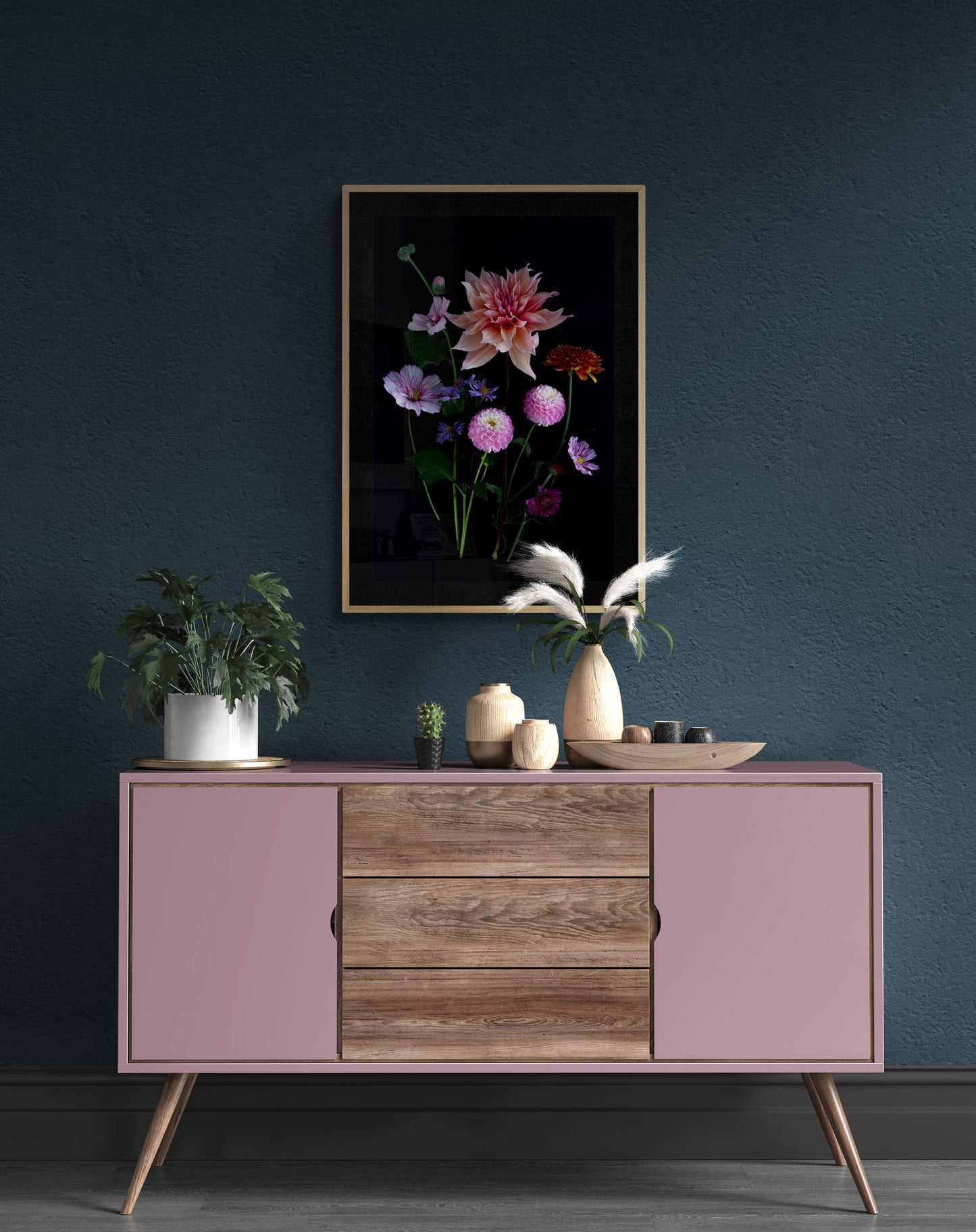 A framed dark botanical print of colourful Dahlias, Cosmos, Asters and Mallow on a black background, hung on a dark teal wall.