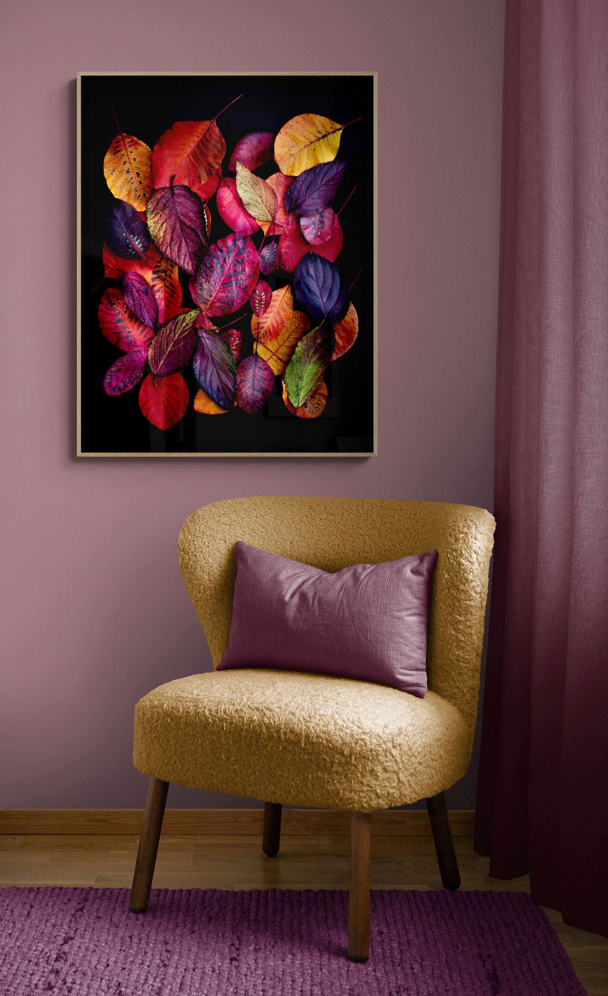 A framed wall art print featuring a cluster of colorful autumn leaves on a black background, displayed above a yellow textured armchair with a purple pillow in a styled room setting.