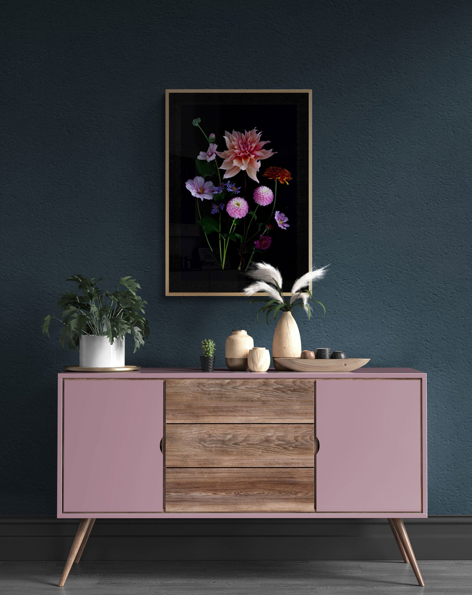 A framed dark botanical print of colourful Dahlias, Cosmos, Asters and Mallow on a black background, hung on a dark teal wall.