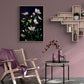 Dark botanical print ofpale pink Picotee hellebores photographed on a black background hung on a pink wall above a wooden chair and accessories.