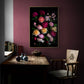 Framed dark botanical print of different coloured roses photographed on a black background hung on a plum coloured wall.